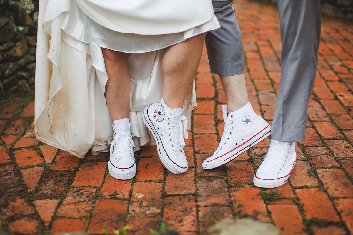 Amie's and Cody's matching white high-top sneakers on the brick path, hers embroidered with small flowers, her dress hem lifted above them