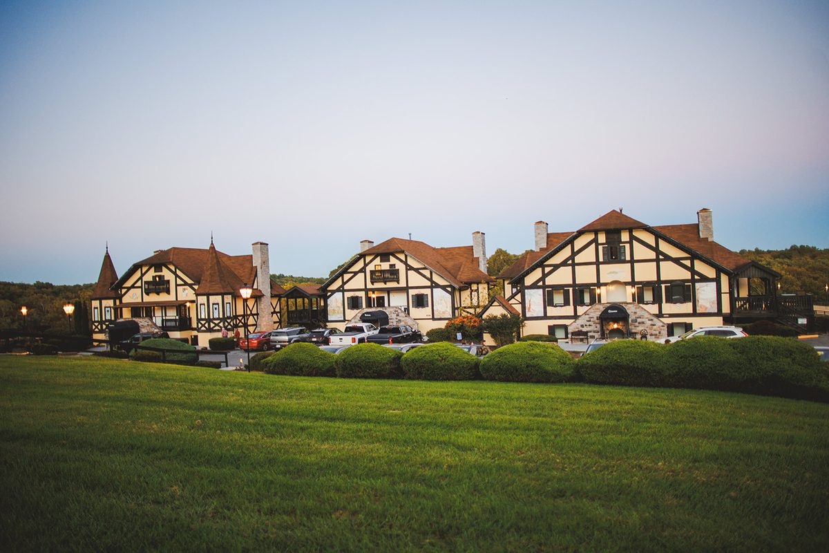 The Bavarian Inn's Tudor chalets at dusk, lamps lit along the drive and hedges dark in the foreground