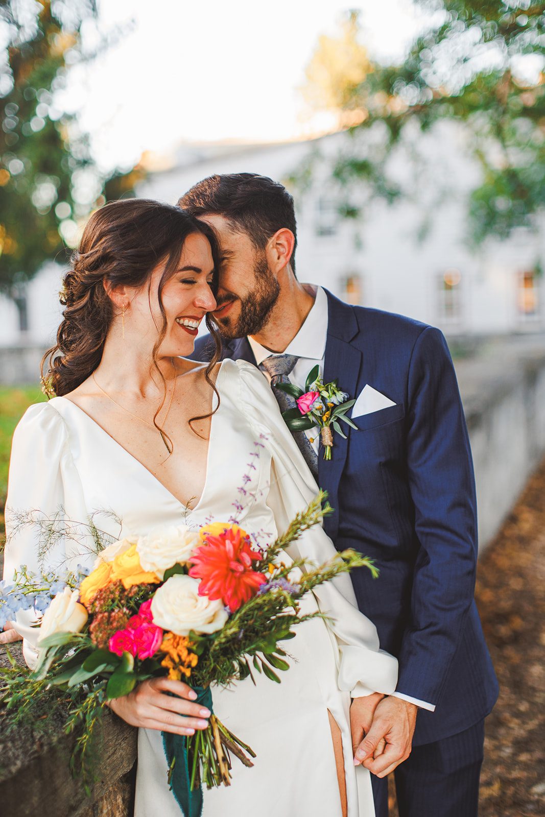 Andrea laughing with her forehead resting against Patrick's, her colorful bouquet held between them in warm evening light