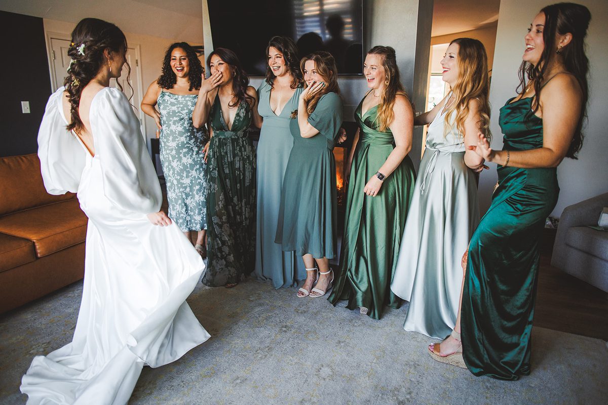 Andrea twirling in her satin gown as her bridal party in shades of green sees her for the first time