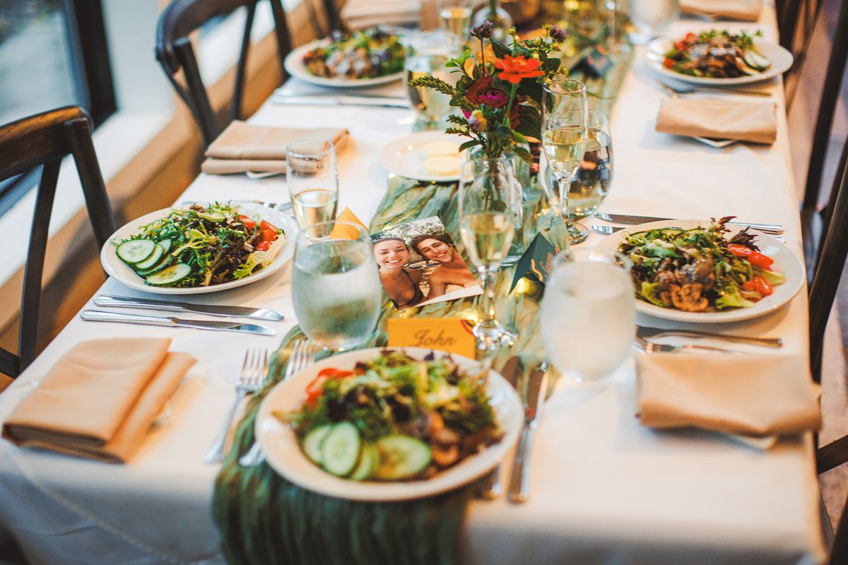 Long reception tables set with salads, sage runners, and small photographs of Andrea and Patrick at each place