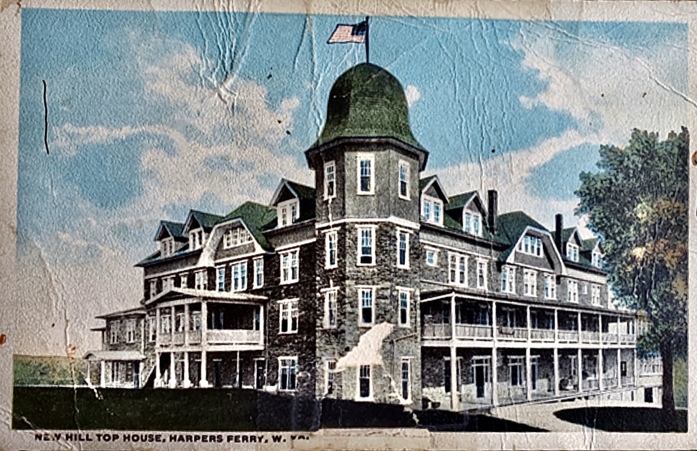 A historic postcard view of the original Hill Top House hotel, a large many-windowed building with wraparound porches and a domed tower standing on the hillside above Harpers Ferry