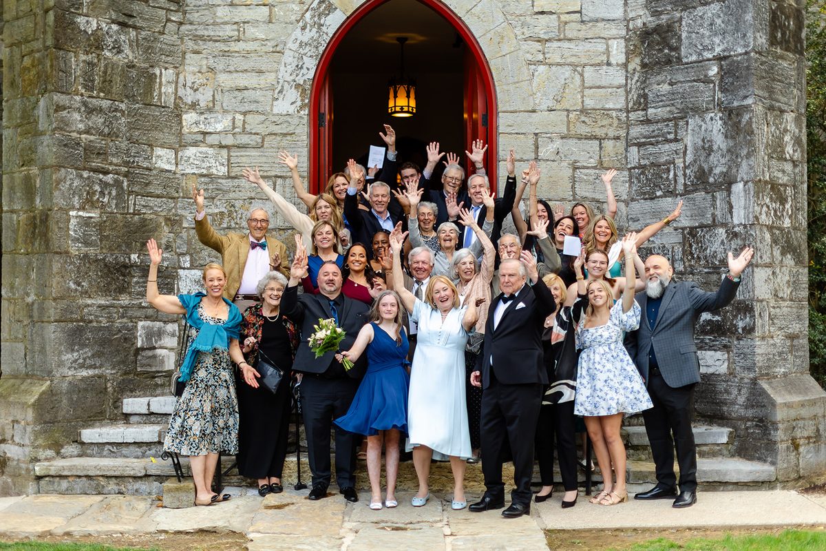 Guests gathered around Mary and Mark at the church doors, everyone cheering with hands raised