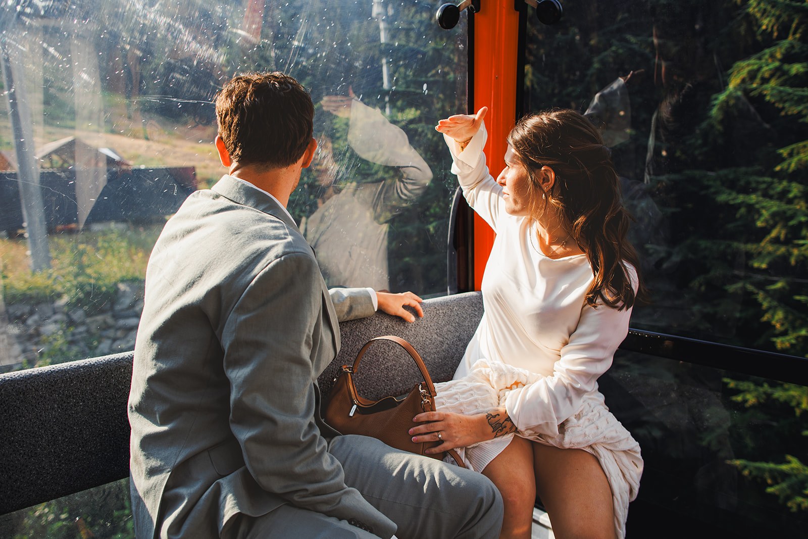 Michaela and AJ alone in the gondola cabin, she is pointing at something out of the window and he is turned to follow her hand