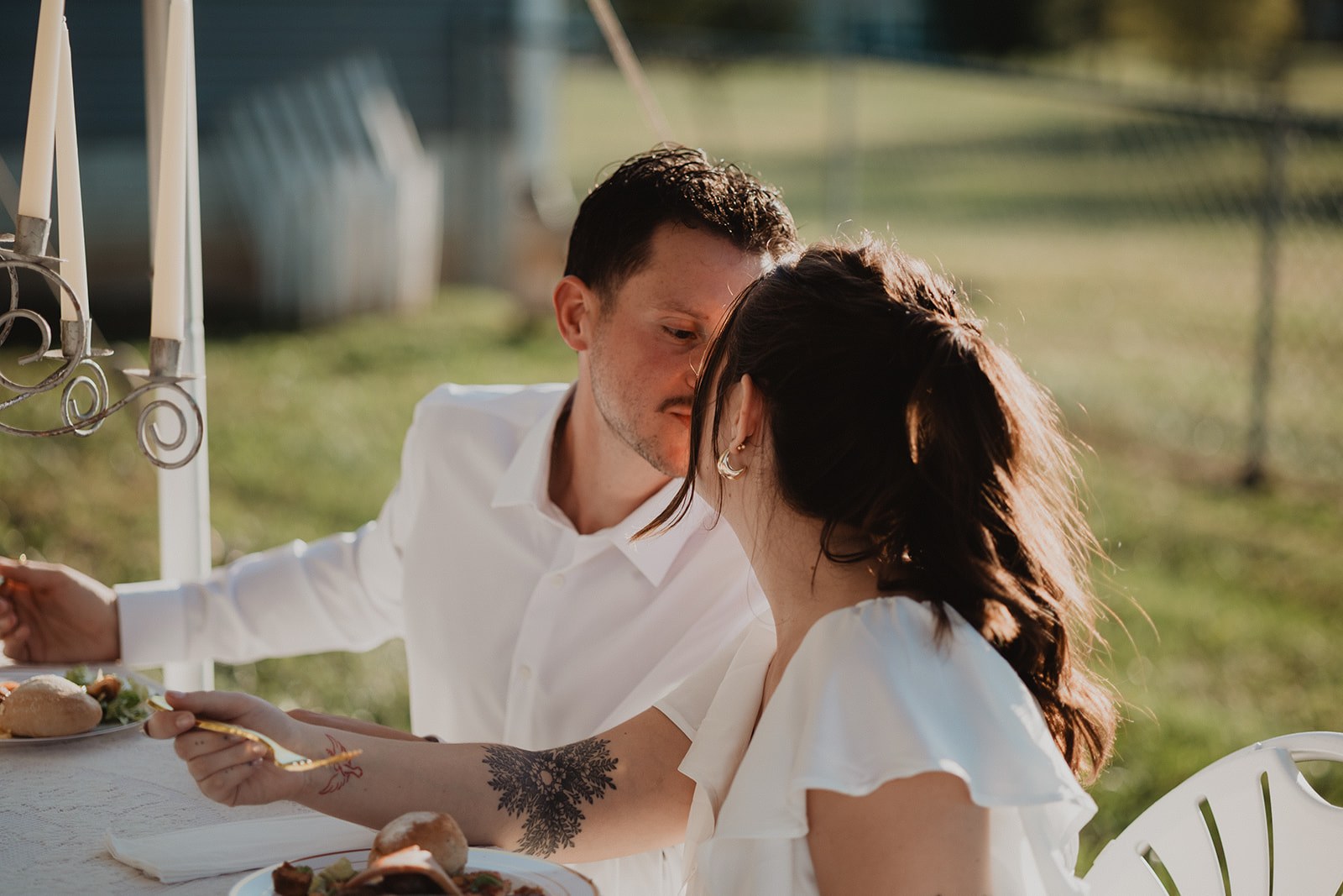 AJ leaning over to kiss the top of Michaela's head at the end of the table while she keeps eating