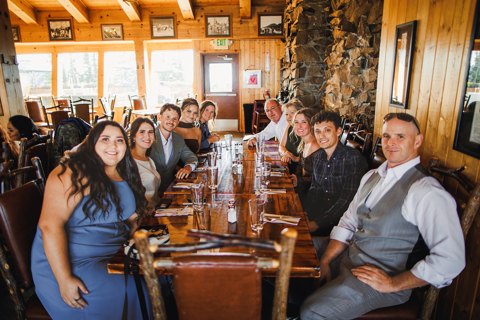 The whole party seated along one long wooden table in the timber dining room at the top of Crystal Mountain, everyone turned toward the camera