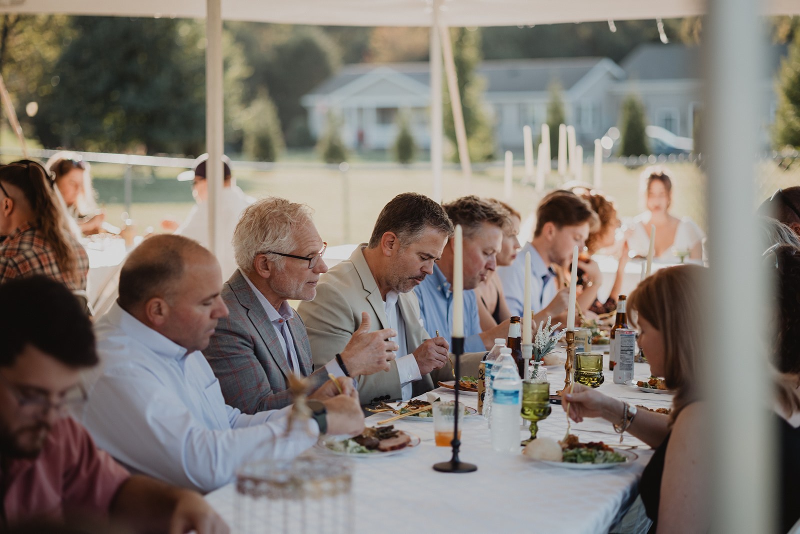 A wider view down the tables with candles lit along the centre and guests leaning in toward each other