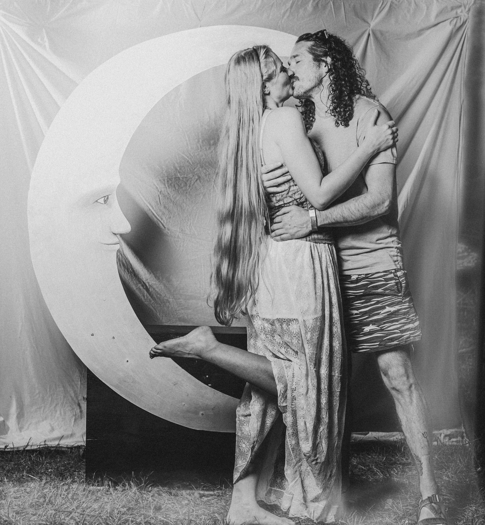 A couple kissing in front of the crescent moon at the Moon Booth, in black and white