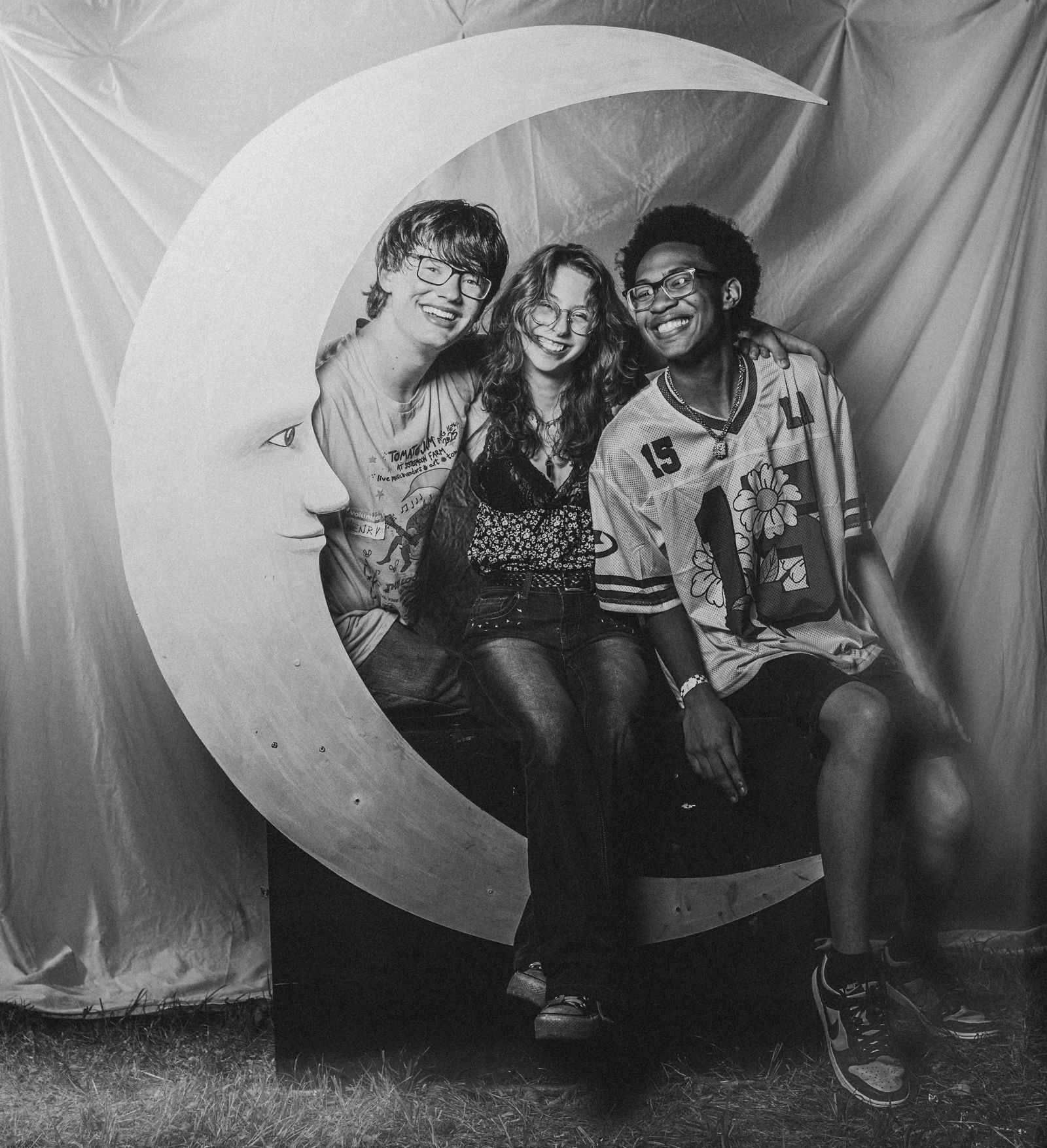 Three friends seated together in the curve of the crescent moon, in black and white