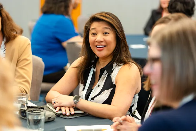 Attendee laughing warmly at a round table during a breakout discussion.