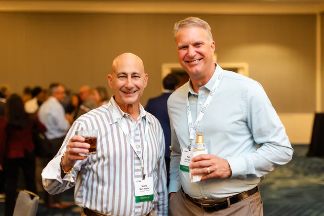 Two attendees toasting with drinks at a networking reception.