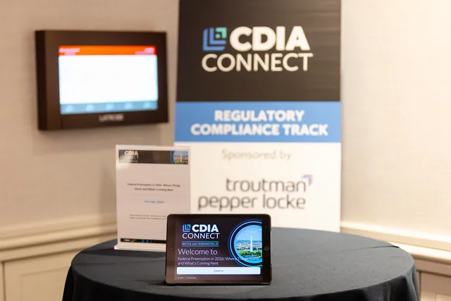 Regulatory compliance track sign at the conference with a welcome display tablet in foreground.