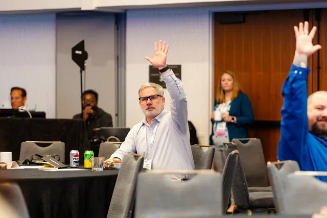 Attendees raising hands to ask questions during a session.