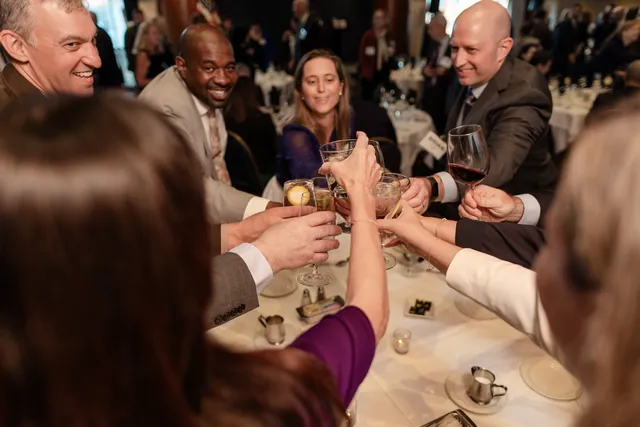 Guests at a table raise glasses together in a toast.