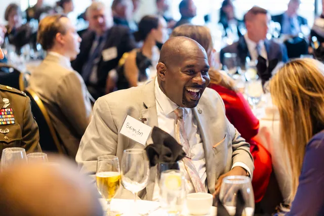 Guest laughs heartily at a round table during the luncheon.