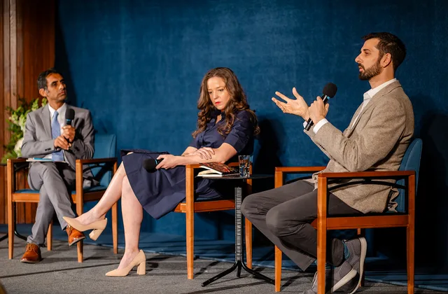 Three-person panel, open gesture from man at right.