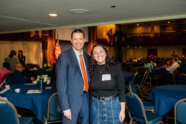 Two attendees posed smiling, ballroom behind.