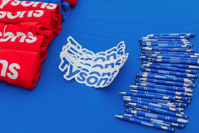 Swag table with logo sticker, pens and red shirts.