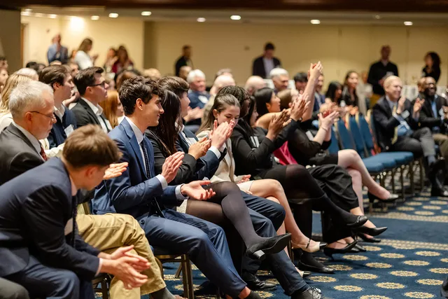 Audience applauding in tight rows.