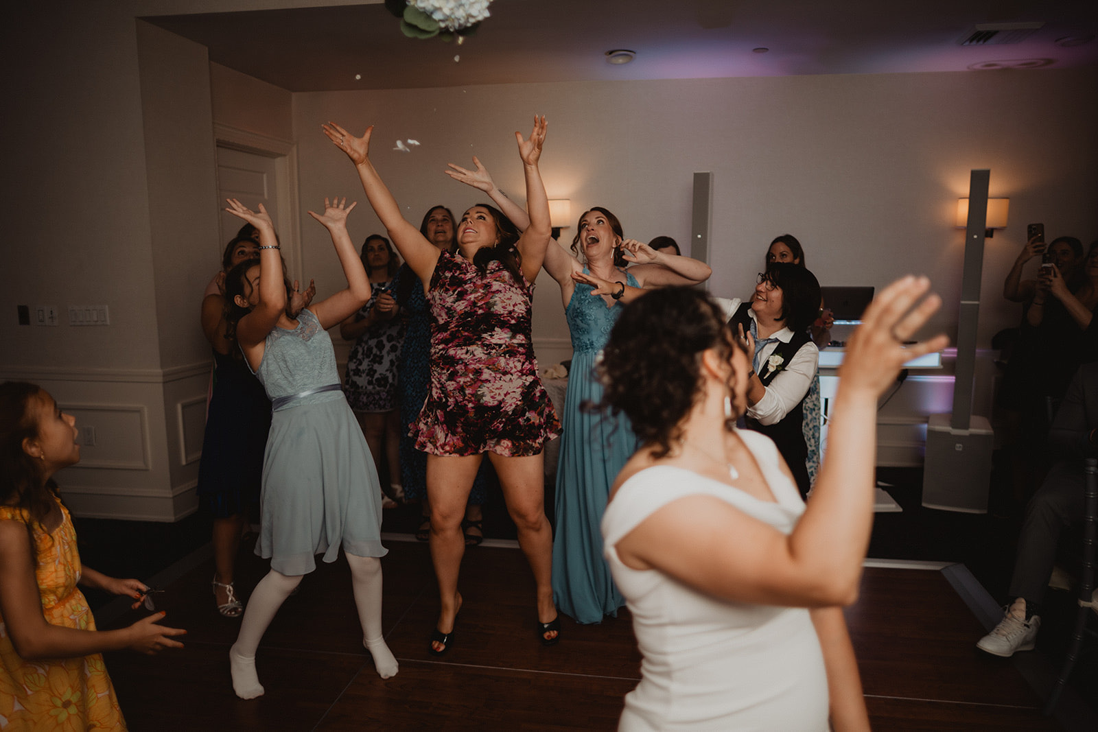 Bouquet toss mid-air, guests reaching up