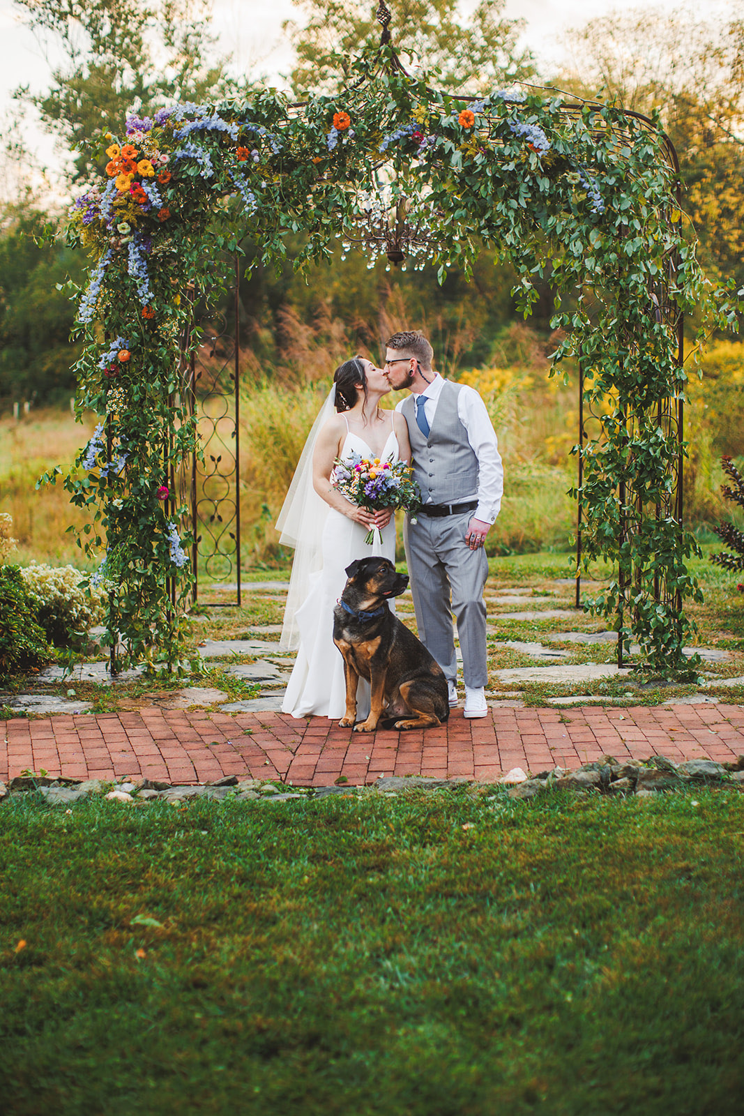 A dog sitting calmly between the couple at the ceremony arch