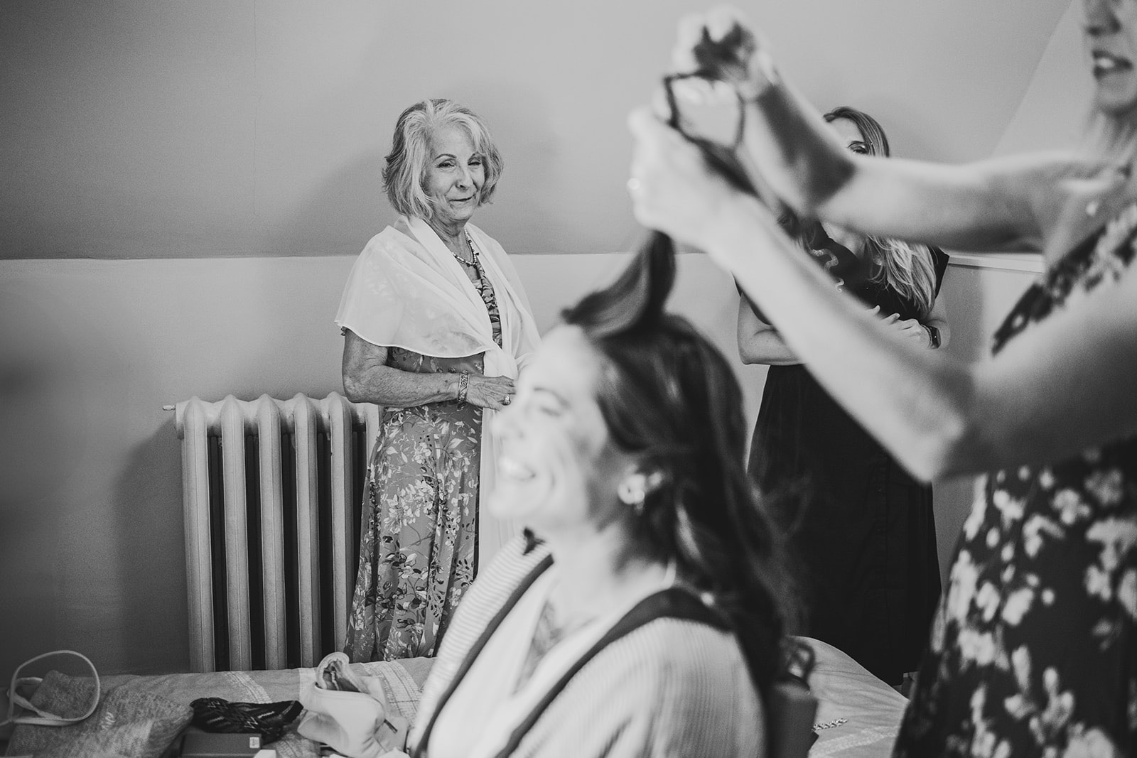 The mother of the bride watching quietly while the bride laughs, getting ready