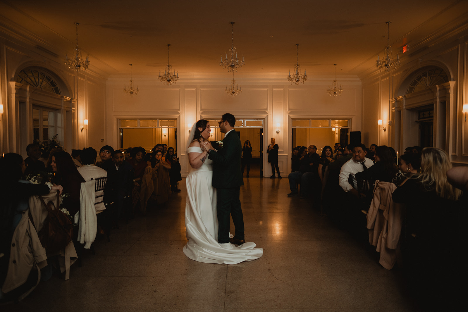 Mersades and Rogelio during their first dance in the ballroom at The Shenandoah, guests seated in the dark around the edges of the room